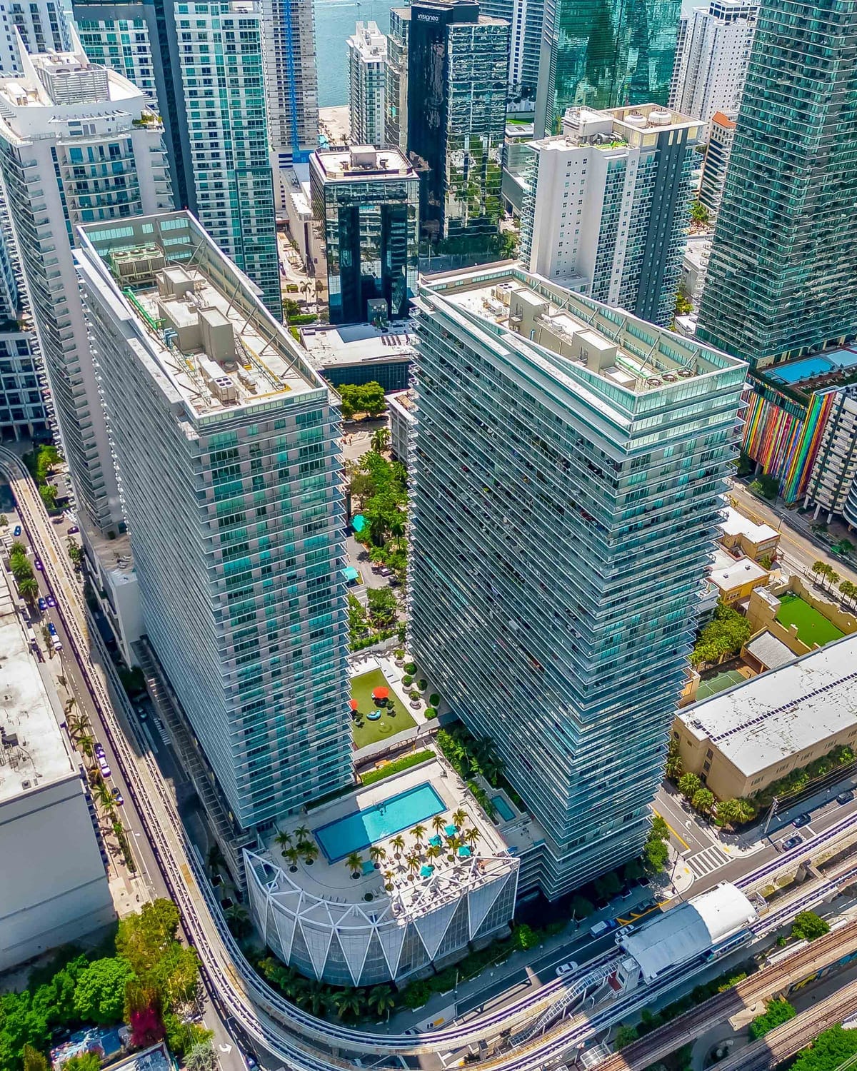 High-angle view of glass residential towers and rooftop amenities among dense city buildings