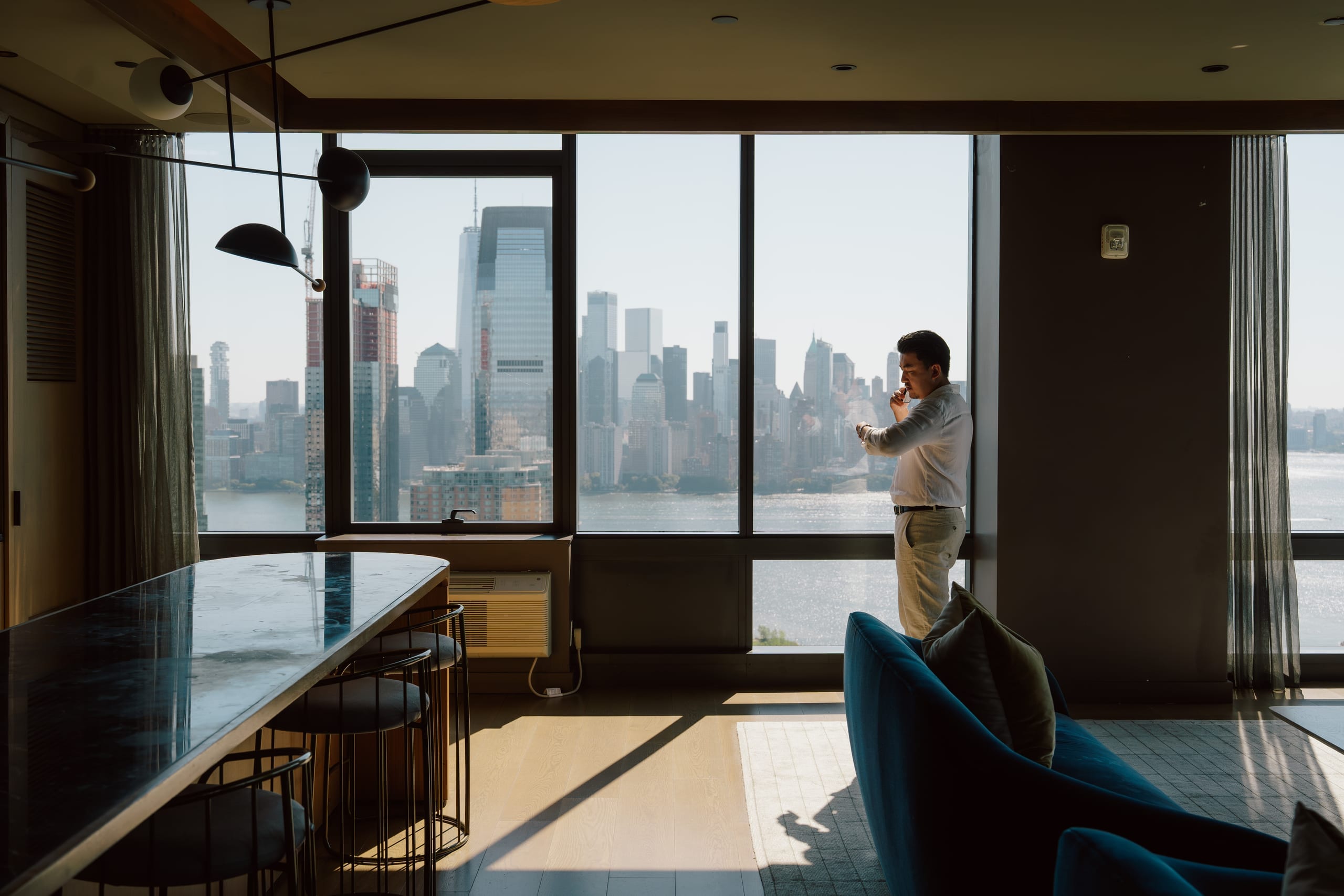 Person standing beside broad skyline windows in kitchen and lounge area