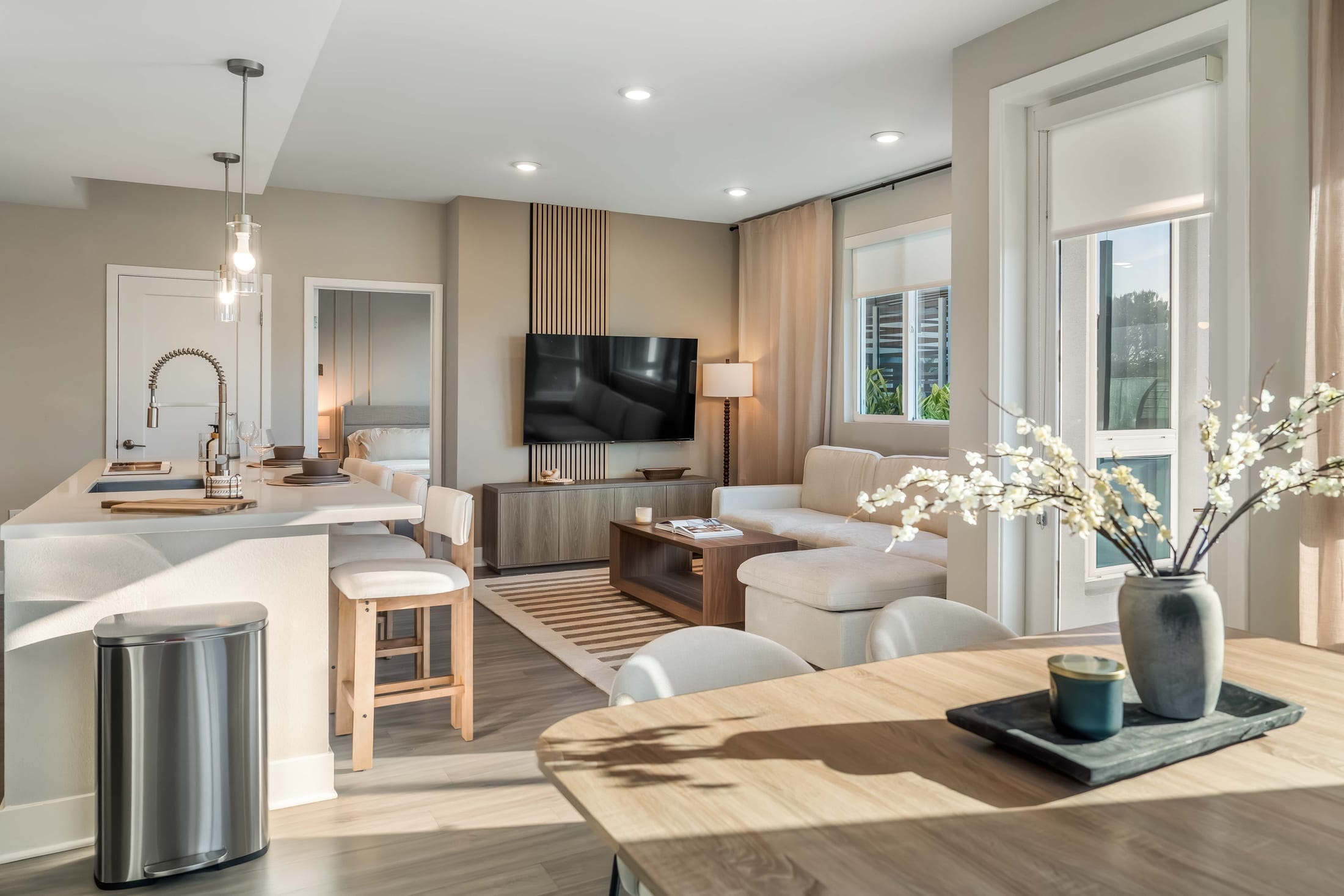 Living room seating beside kitchen island and dining table displaying vase of flowers