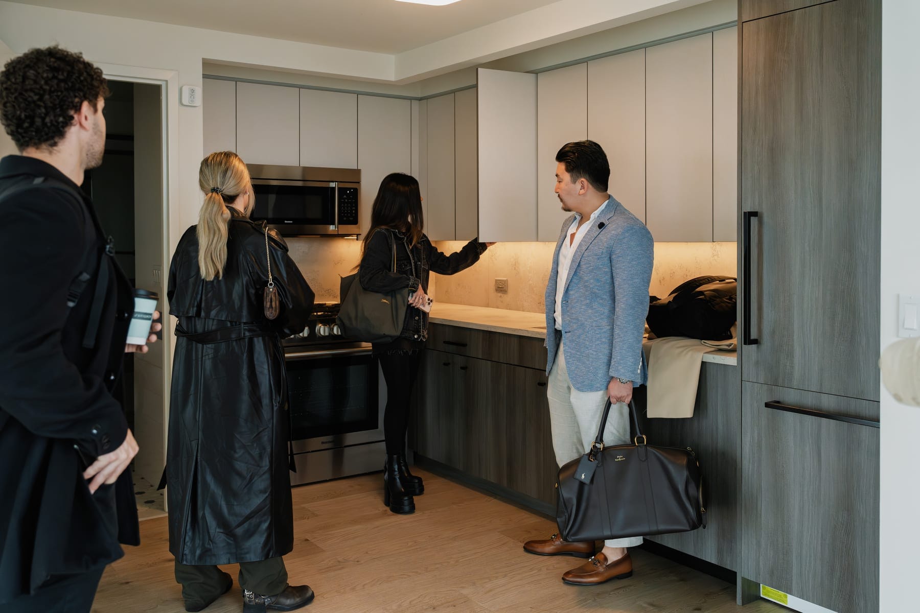 Four people standing together in a kitchen beside cabinets and countertop