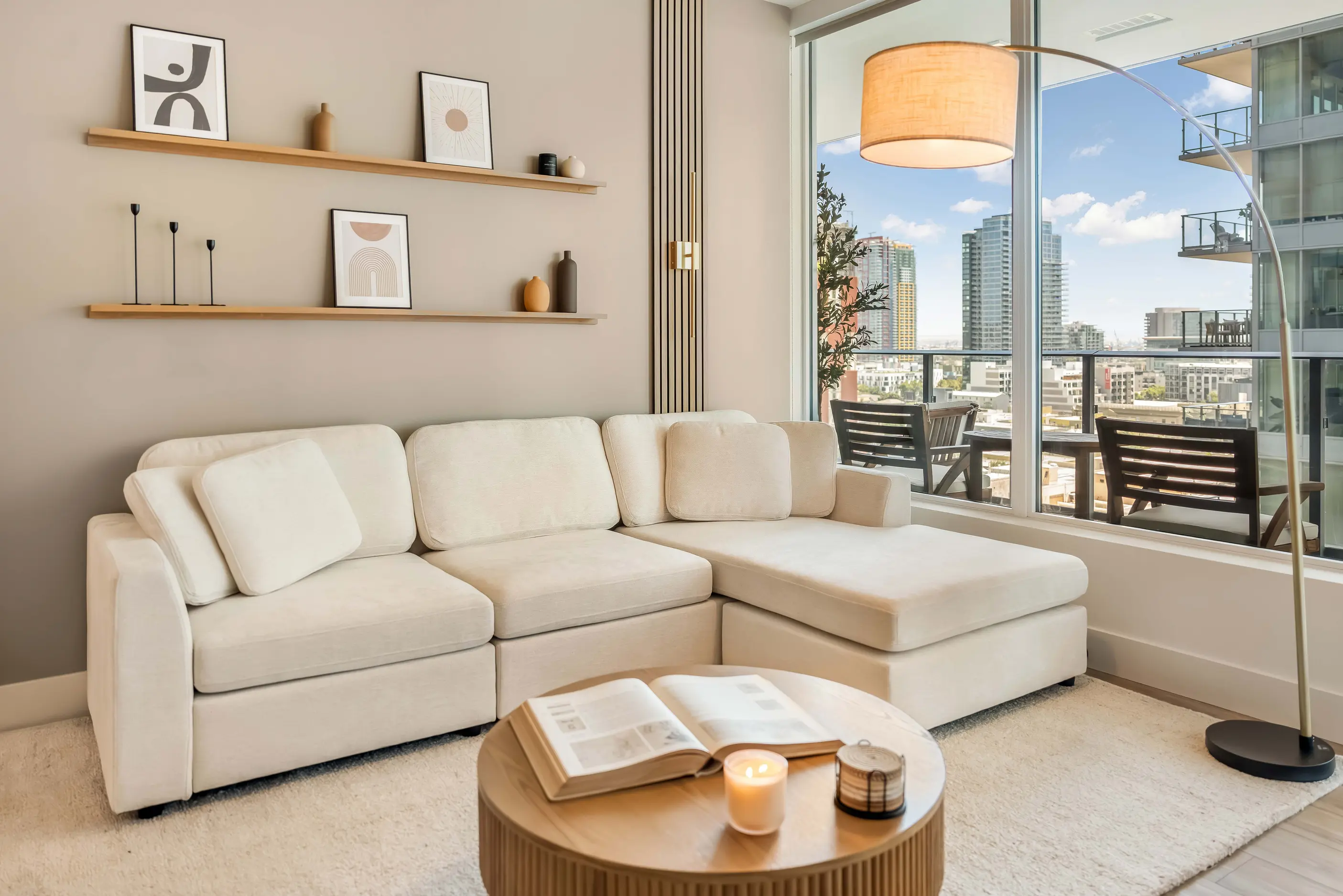 White sectional sofa beneath display shelves beside large window and floor lamp at The Palazzo by World Class® in San Diego