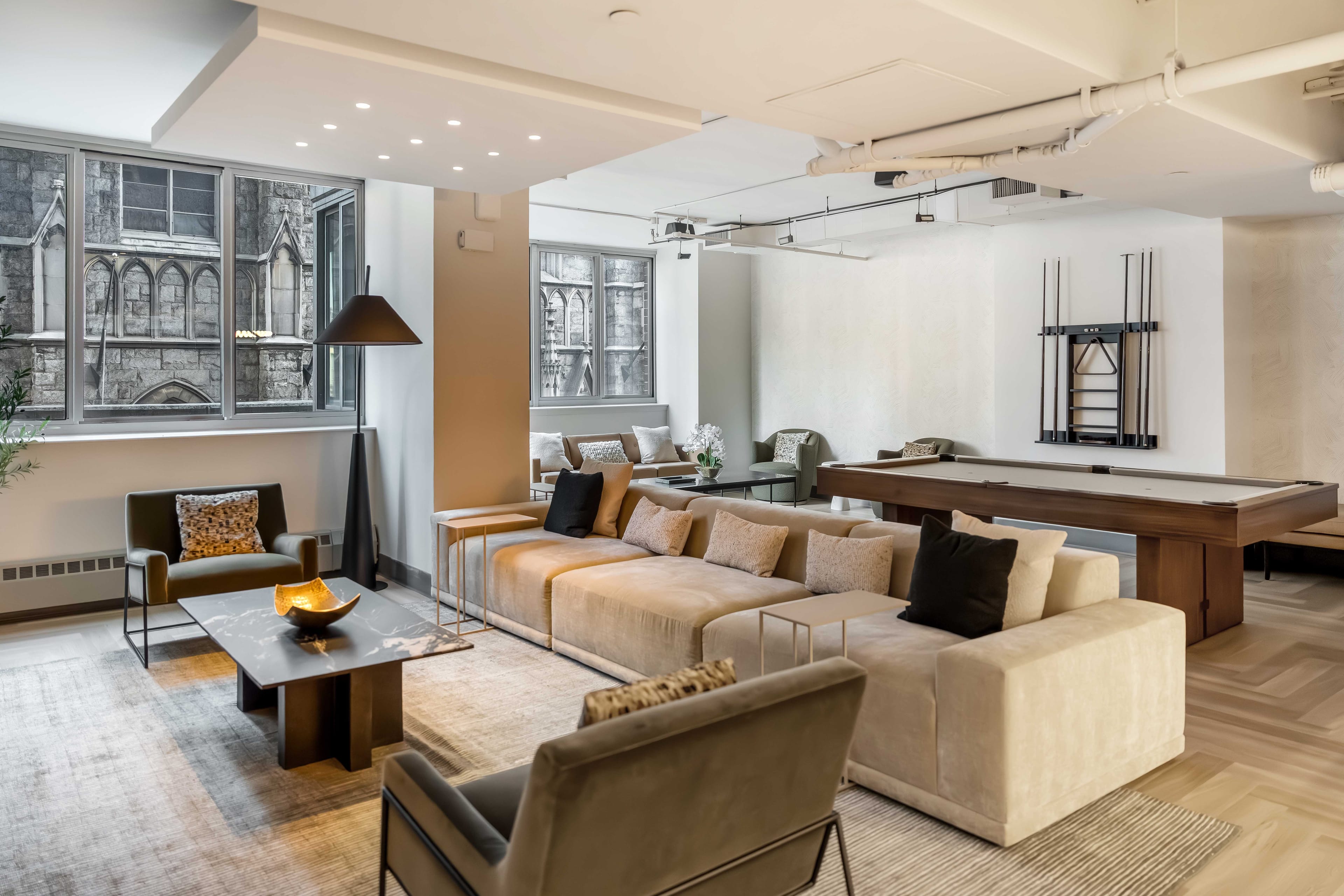 Shared lounge with cream sofas, coffee table, pool table, and large windows at Hudson Landing in New York City