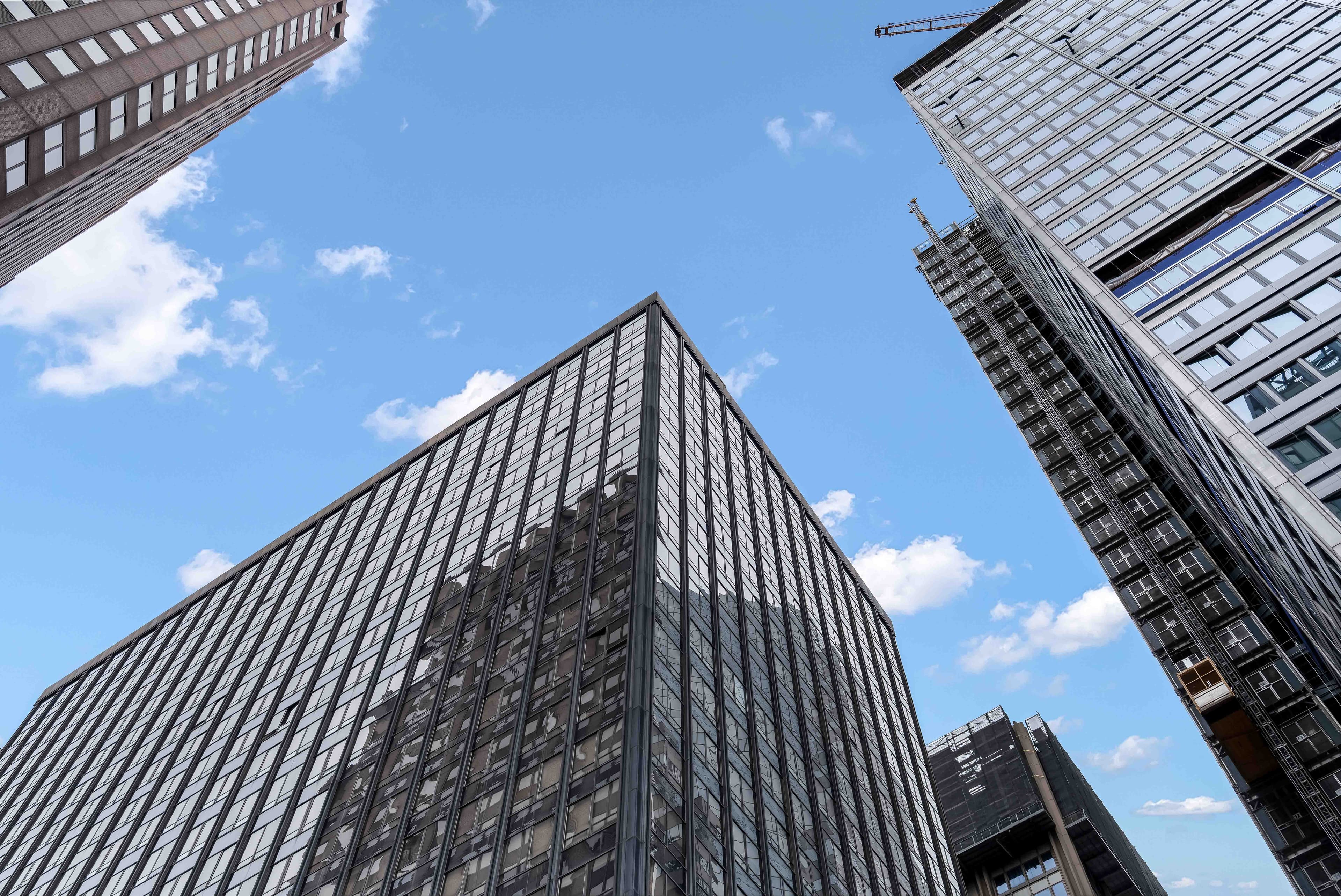 Upward view of tall buildings with rows of windows surrounding an open blue sky at 95 Wall in New York