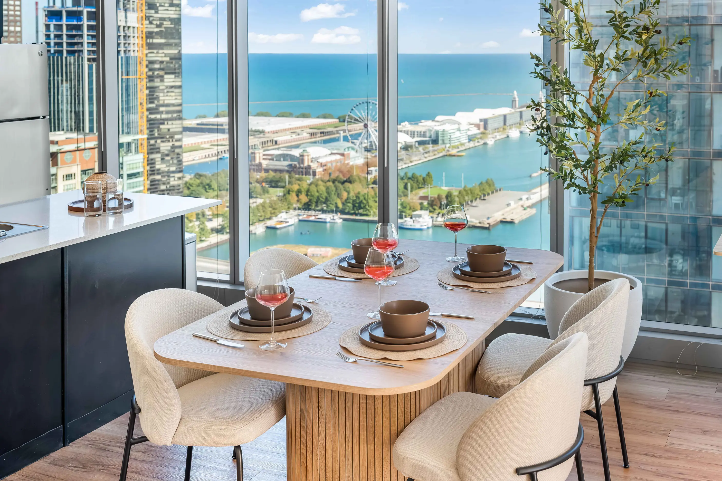 Dining table set with bowls and glasses beside windows overlooking marina and water at The Atlas Highrise in Chicago